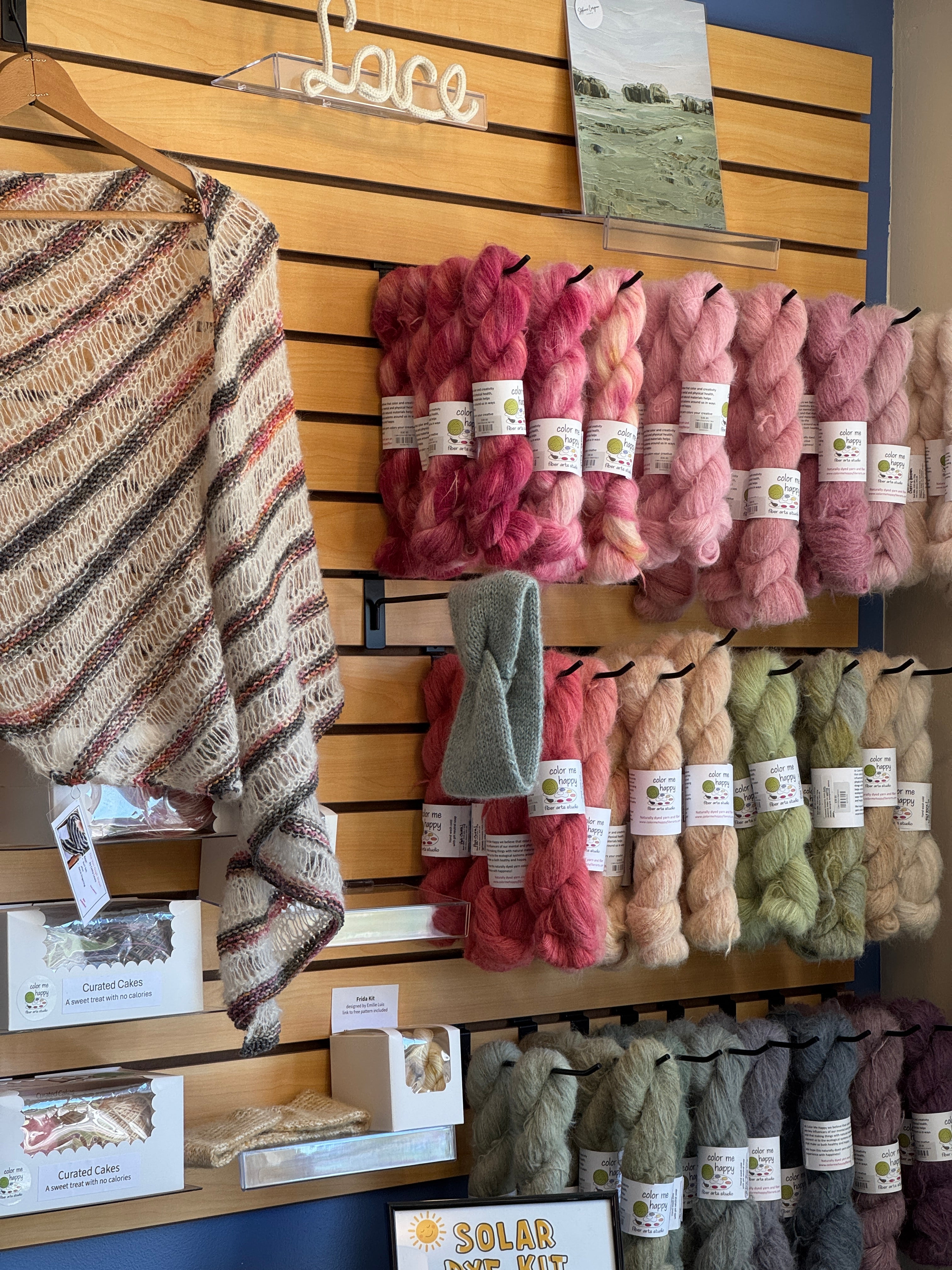 A slat wall full of lace weight yarn featuring suri silk alpaca naturally dyed by Color Me Happy Fiber Arts