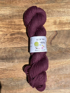 burgundy skein of yarn with a label on a wooden surface