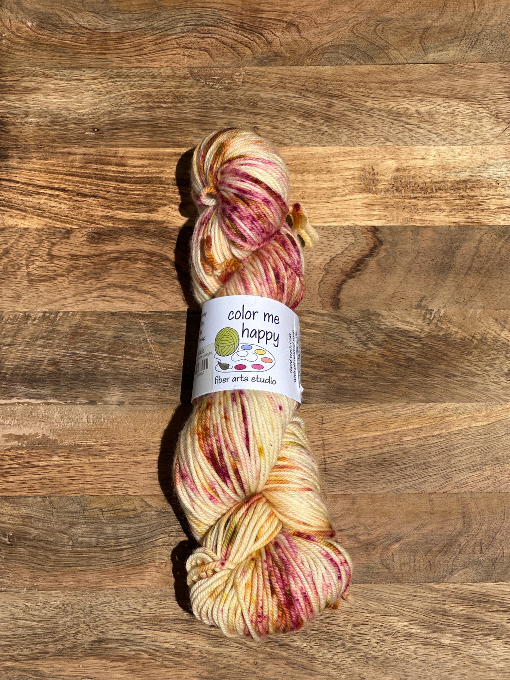 skein of speckled yarn with a label on a wooden surface
