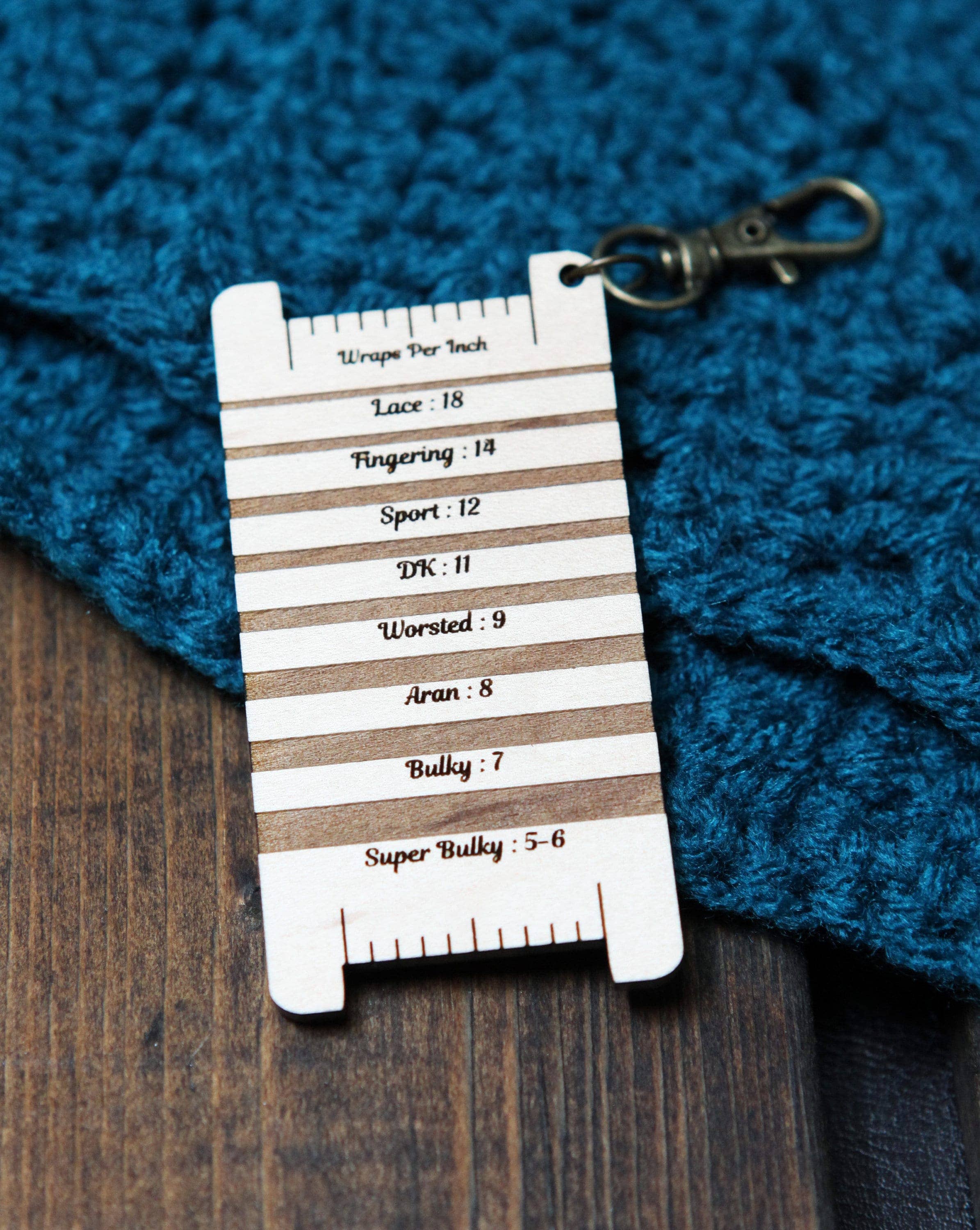 Knitting gauge ruler with yarn weight chart on a blue knitted fabric background