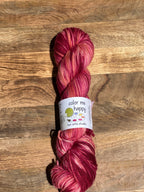 red variegated skein of yarn with a label on a wooden surface