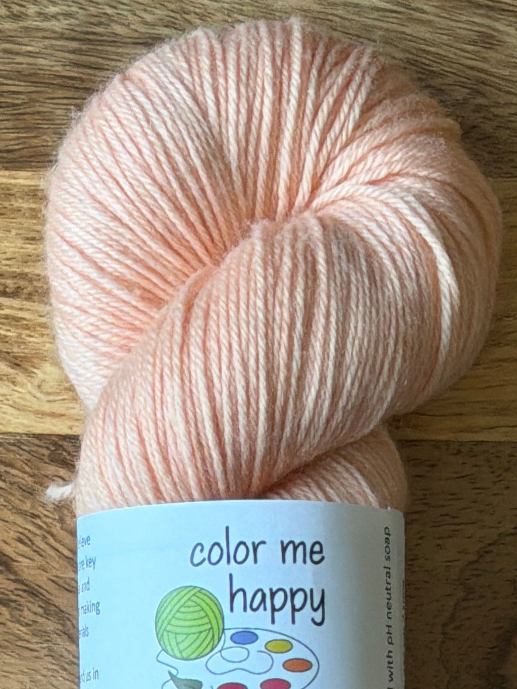 Ligh pink yarn with a label on a wooden surface