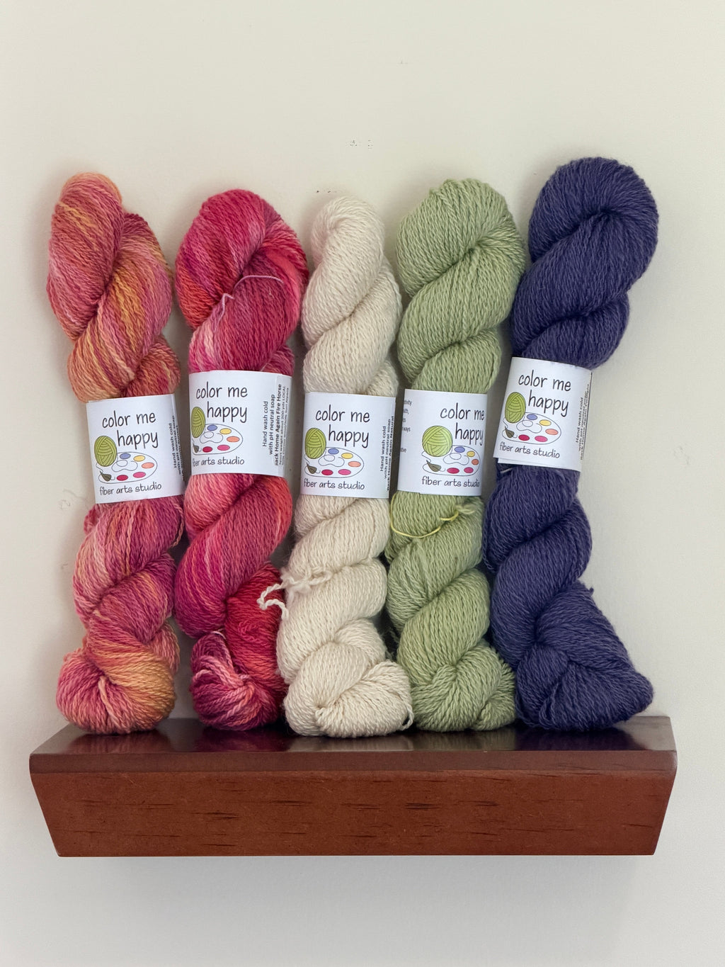 Lifestyle picture of 5 colorful skeins of yarn on shelf