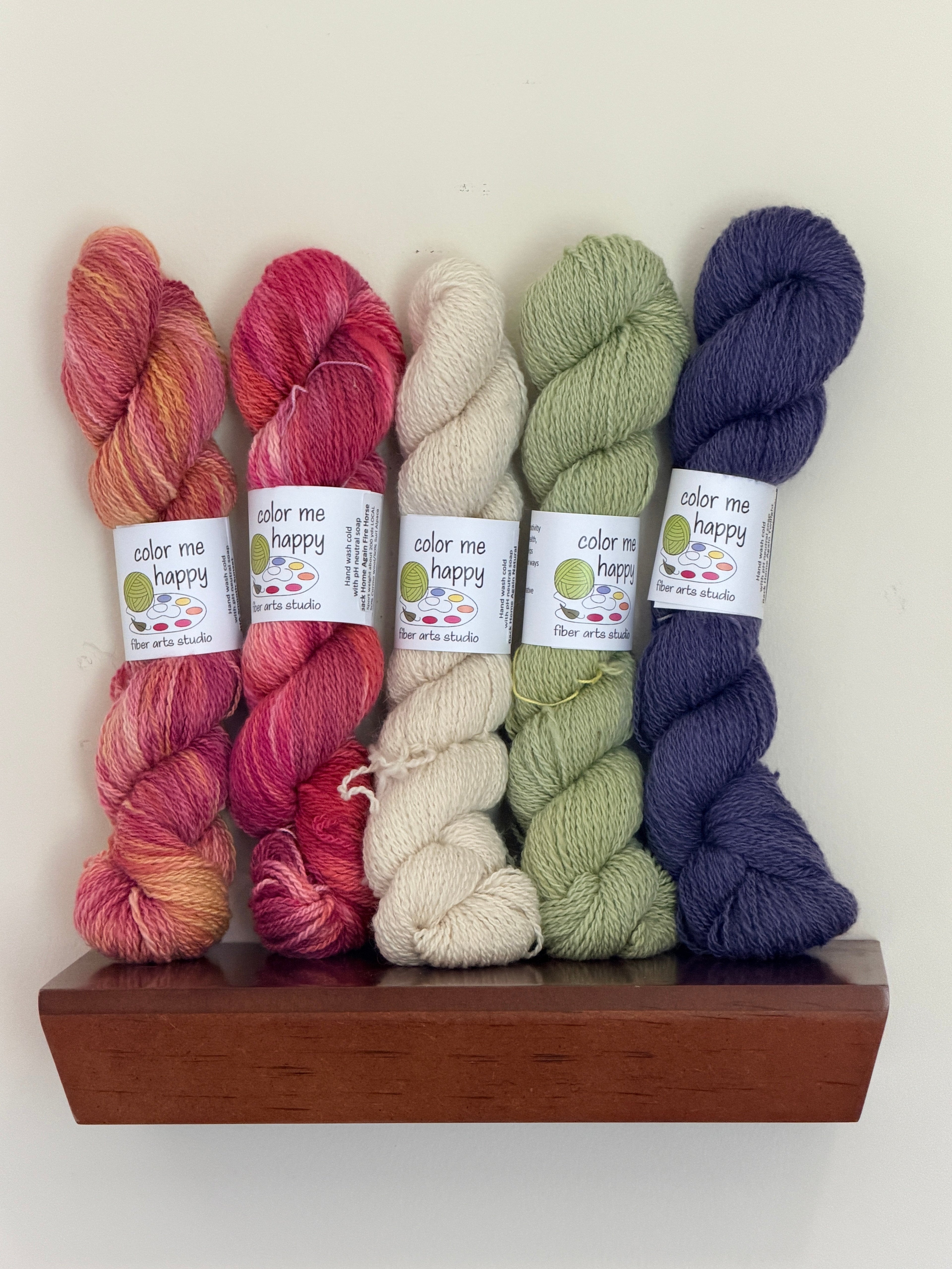 Lifestyle picture of 5 colorful skeins of yarn on shelf