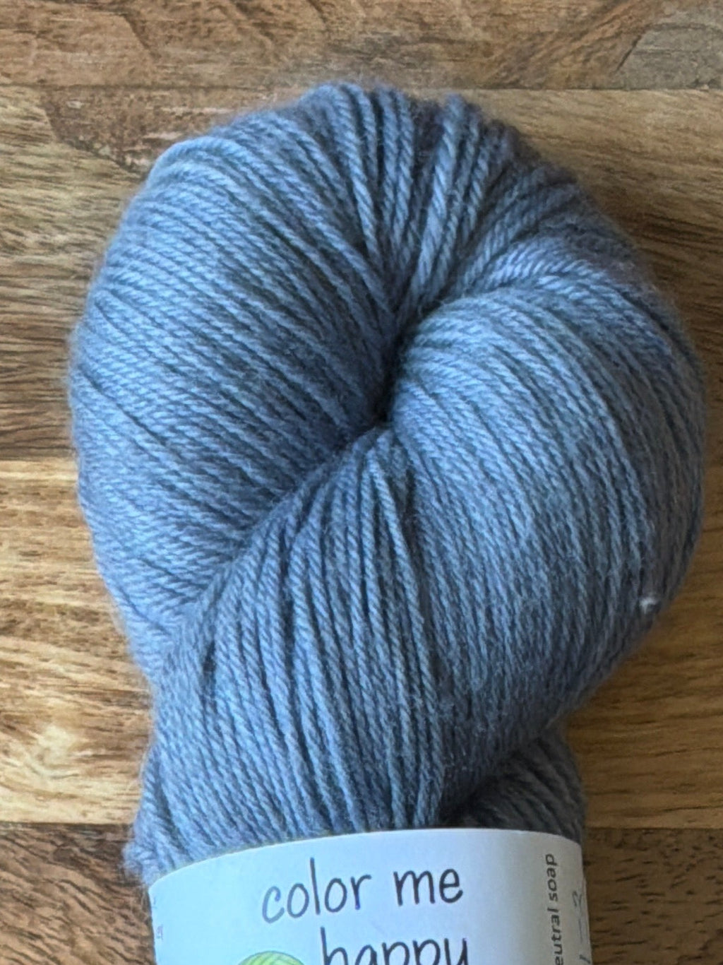Blue skein of yarn with a label on a wooden surface
