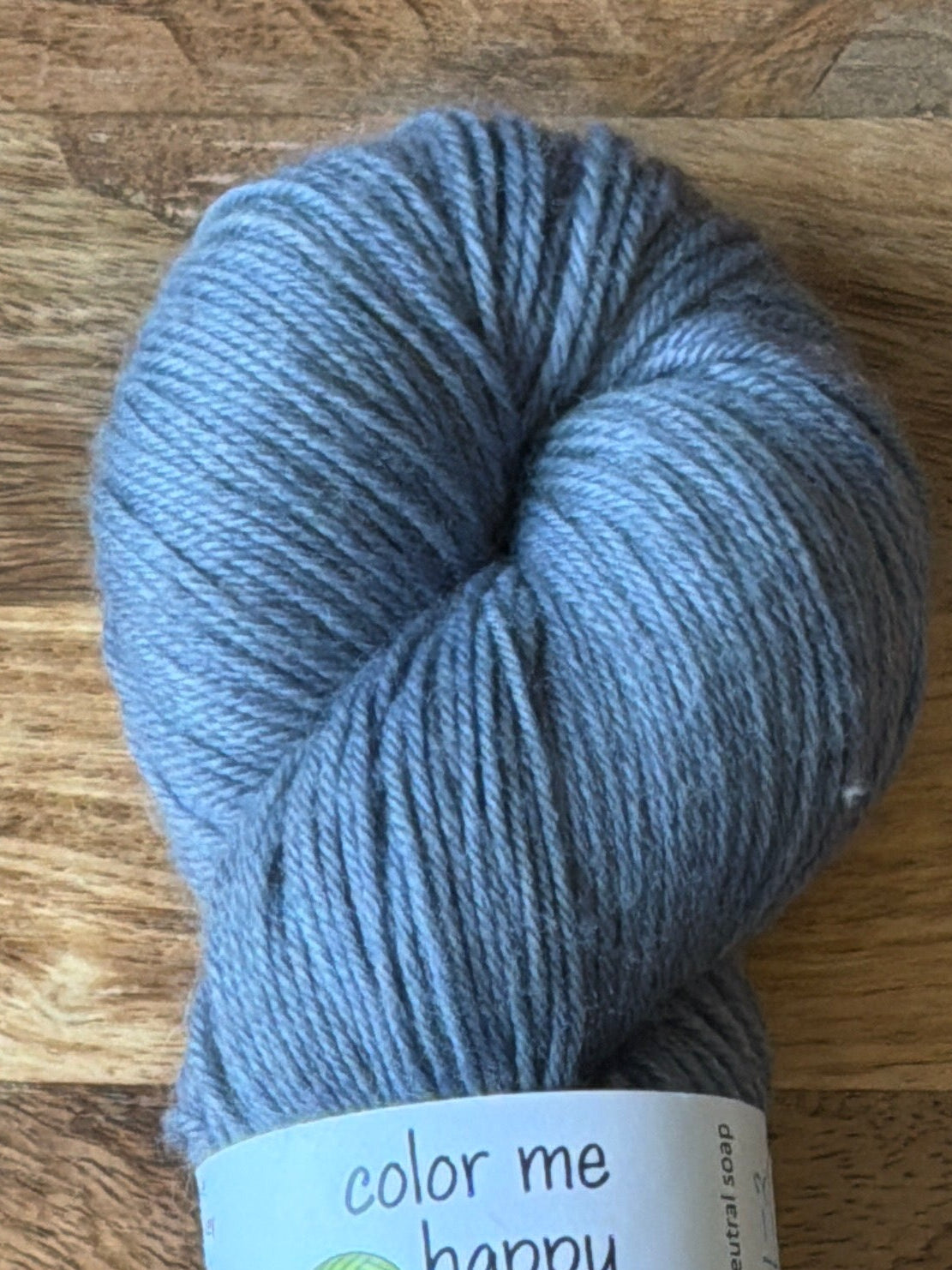 Blue skein of yarn with a label on a wooden surface