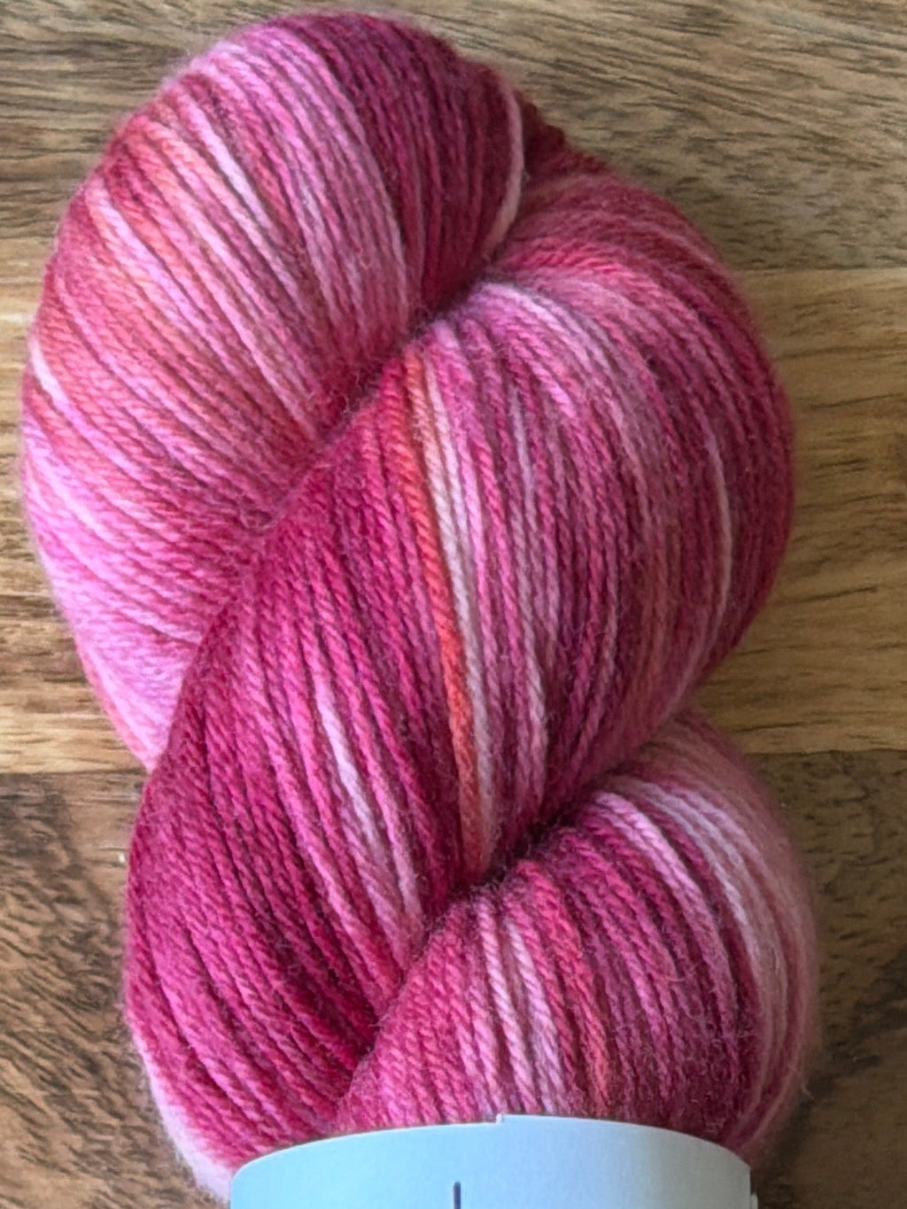 Pink skein of yarn with a label on a wooden surface