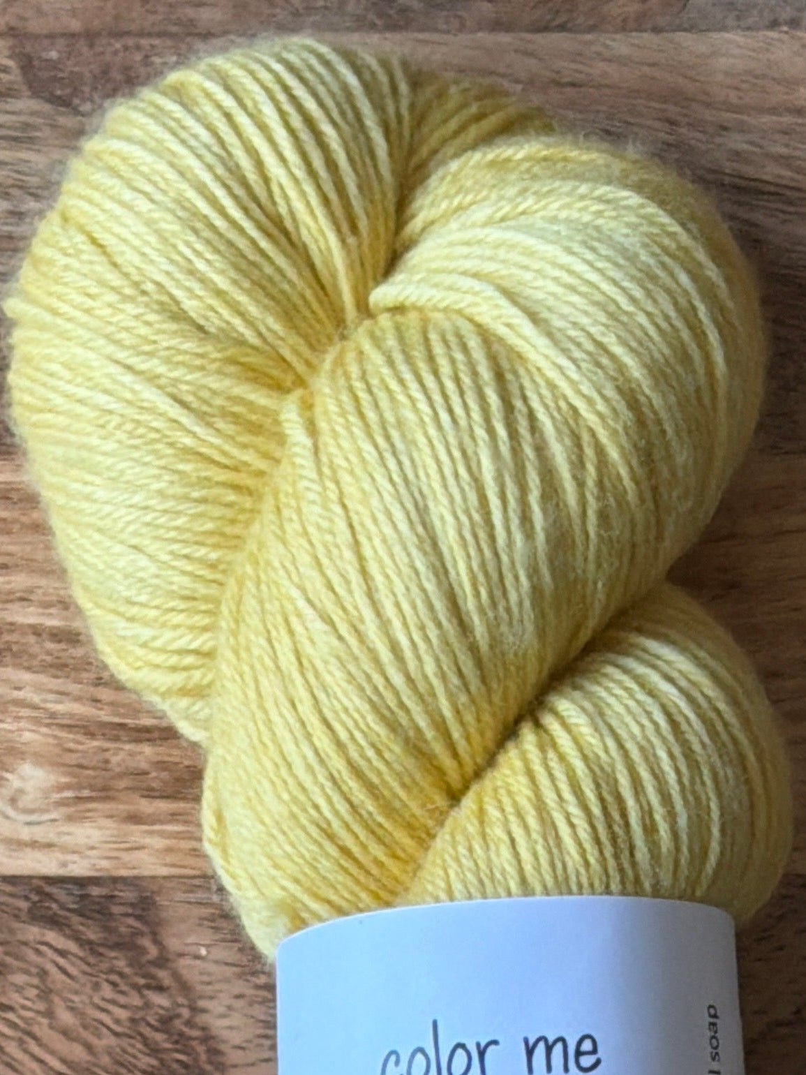 Yellow skein of yarn with a label on a wooden surface