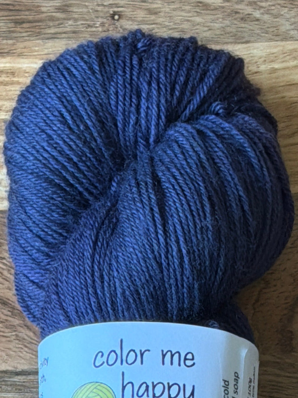 Blue skein of yarn with a label on a wooden surface