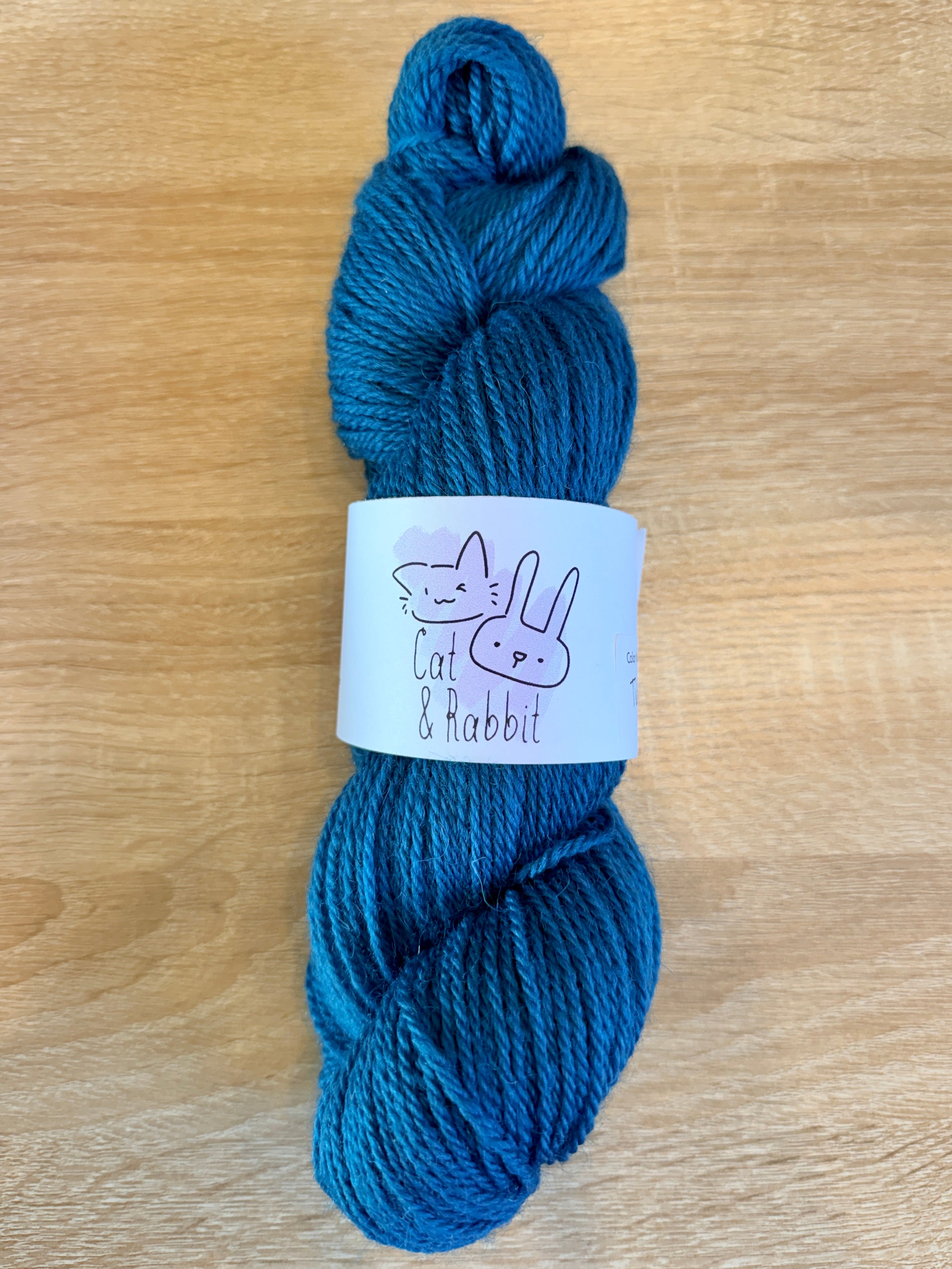 Blue skein of yarn with a label on a wooden surface