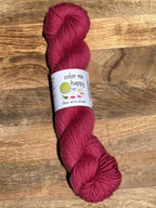 Cherry red skein of yarn with a label on a wooden surface
