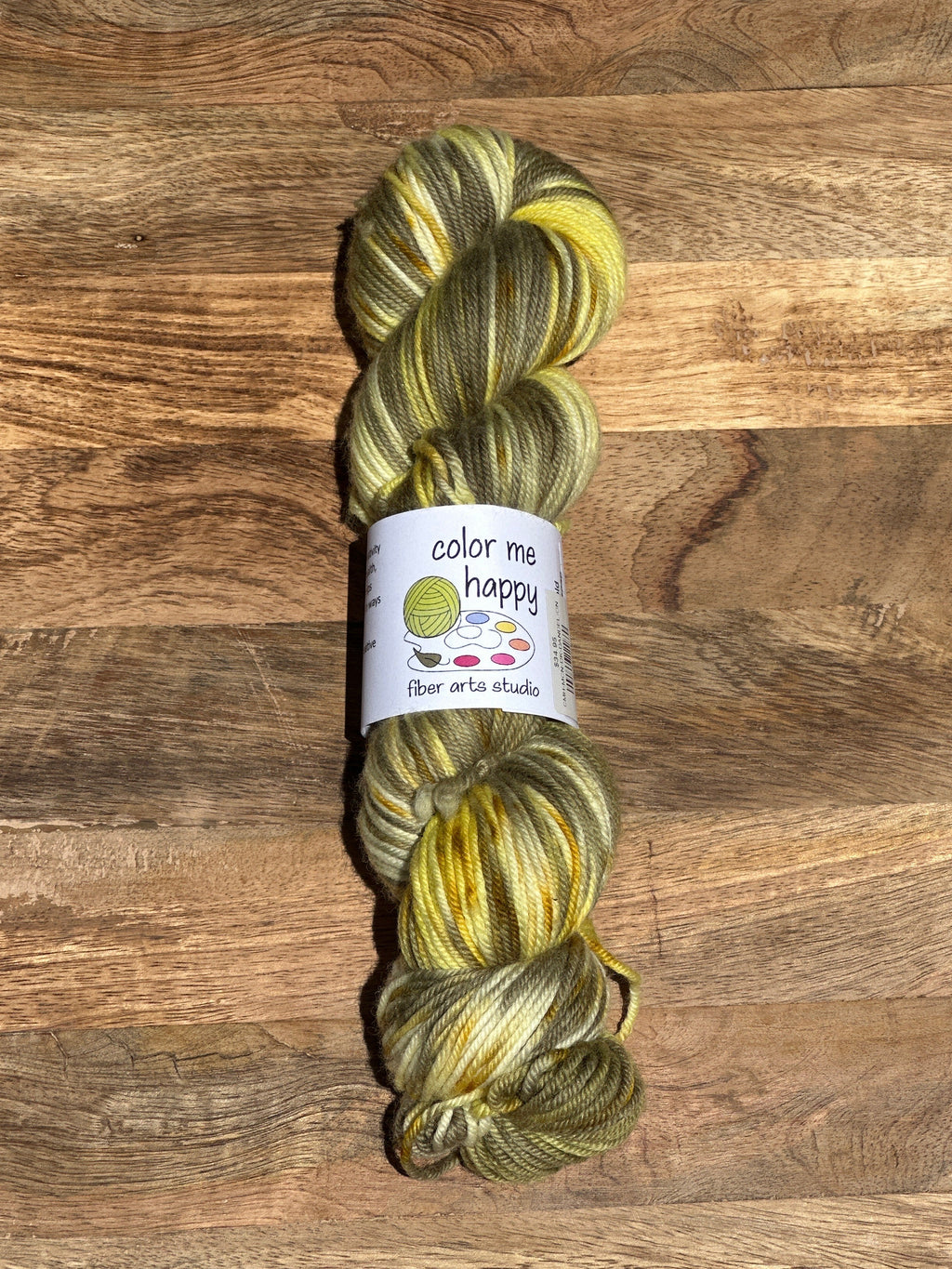 green and yellow Yarn skein with a label on a wooden surface
