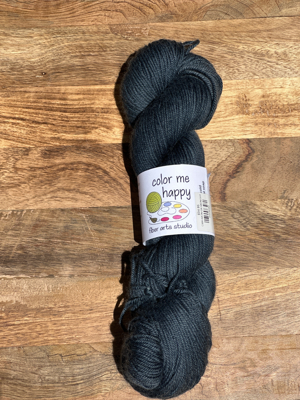 Dark blue skein of yarn with a label on a wooden surface