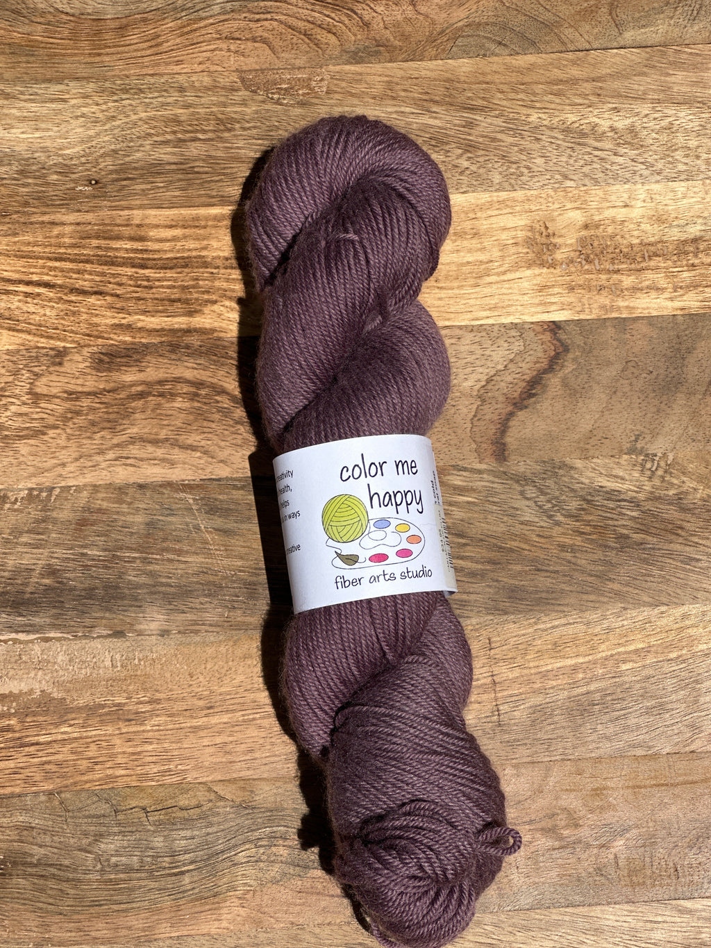 Purple skein of yarn with a label on a wooden surface