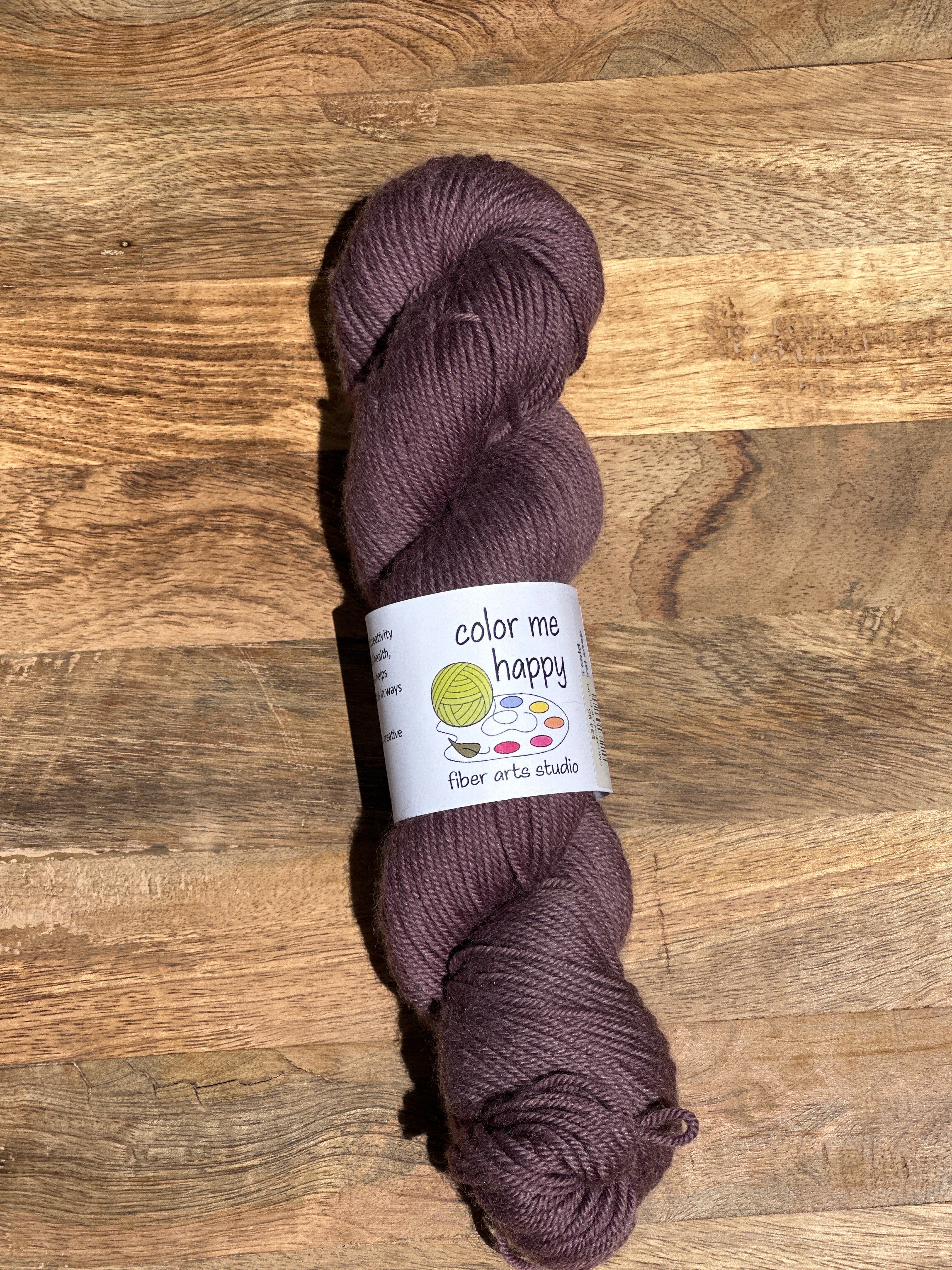 Purple skein of yarn with a label on a wooden surface