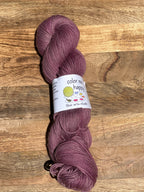Purple skein of yarn with a label on a wooden surface