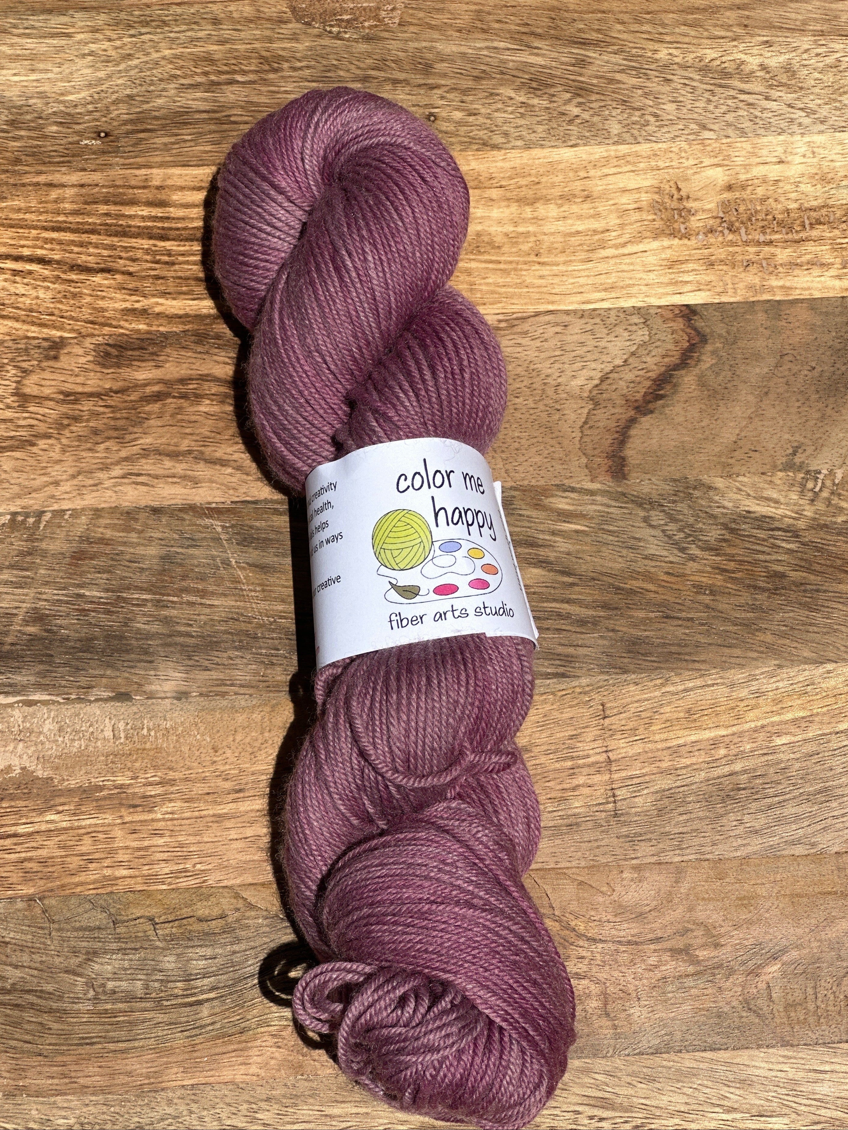 Purple skein of yarn with a label on a wooden surface