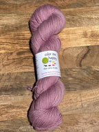 Lilac skein of yarn with a label on a wooden surface