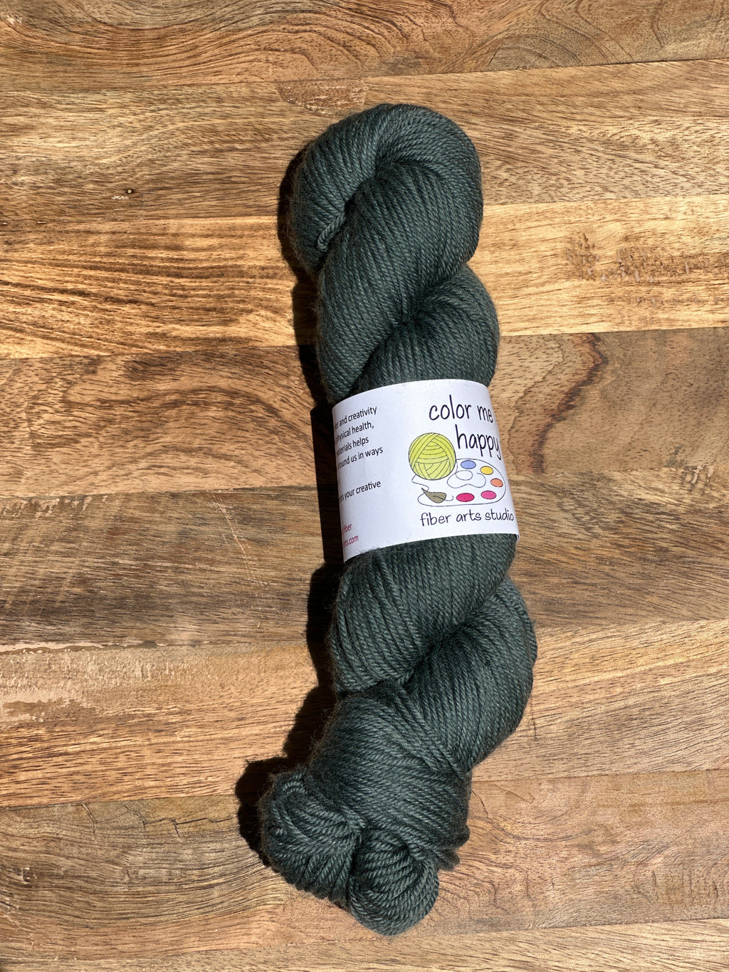 Dark green skein of yarn with a label on a wooden surface