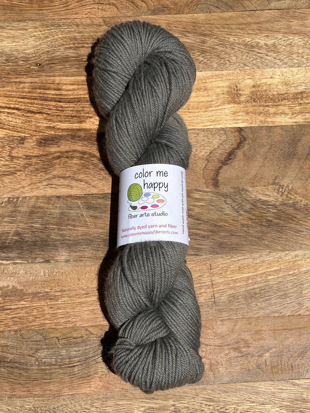 Gray skein of yarn with a label on a wooden surface