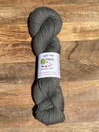 Gray skein of yarn with a label on a wooden surface
