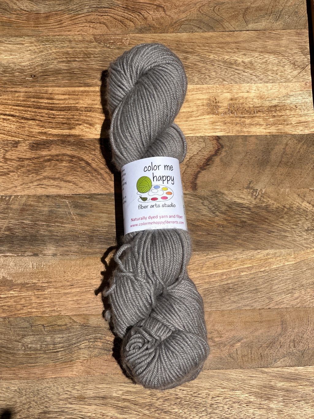 Gray skein of yarn with a label on a wooden surface