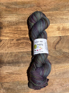 Multicolored blue/purple/green skein of yarn with a label on a wooden surface