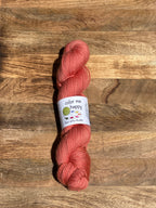 melon-colored skein of yarn with a label on a wooden surface