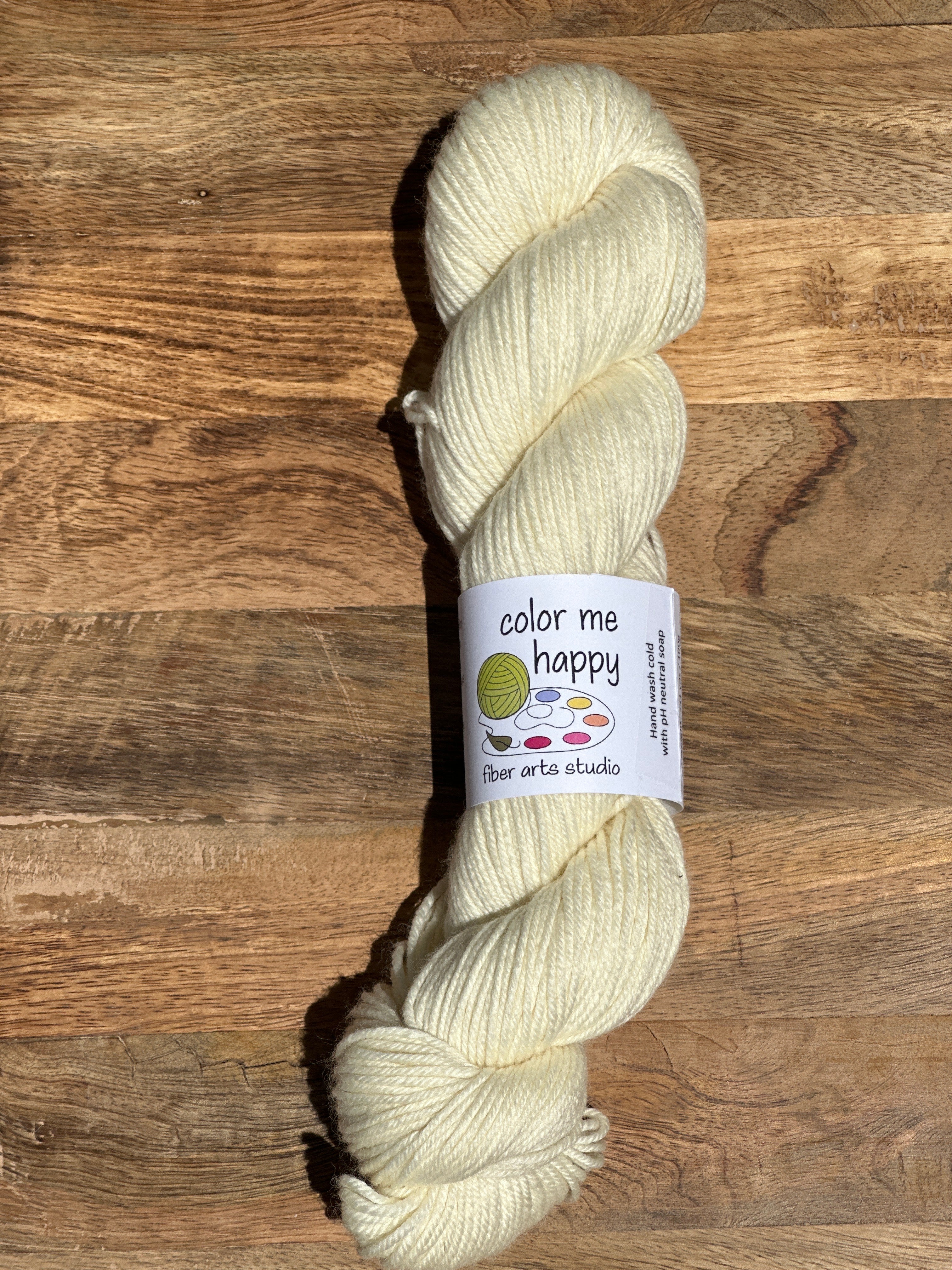 Cream-colored skein of yarn with a label on a wooden surface