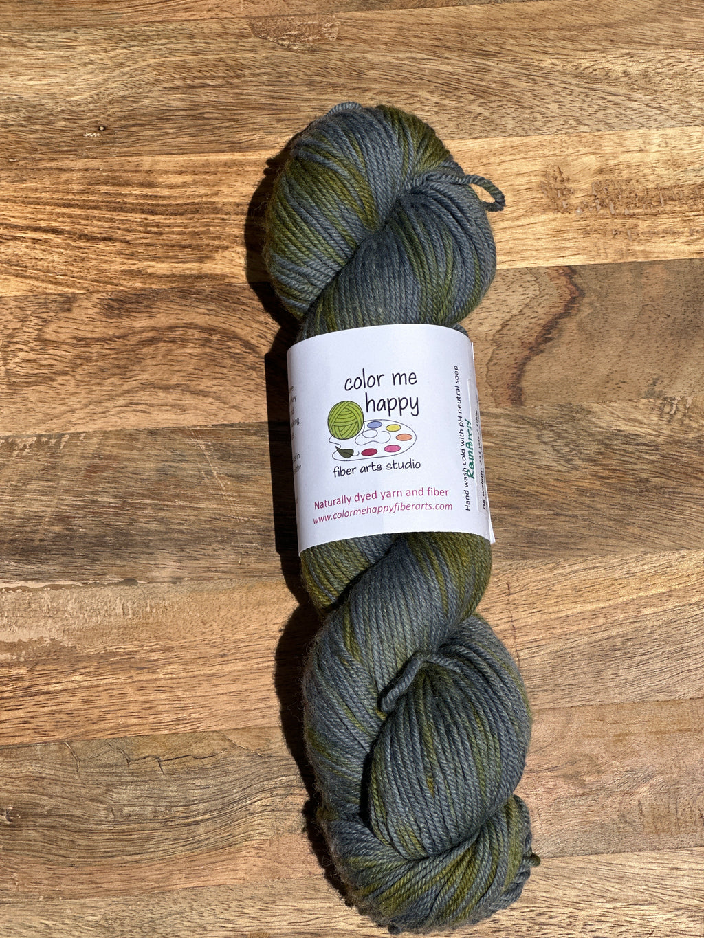  skein of green and blue variegated yarn with a label on a wooden surface
