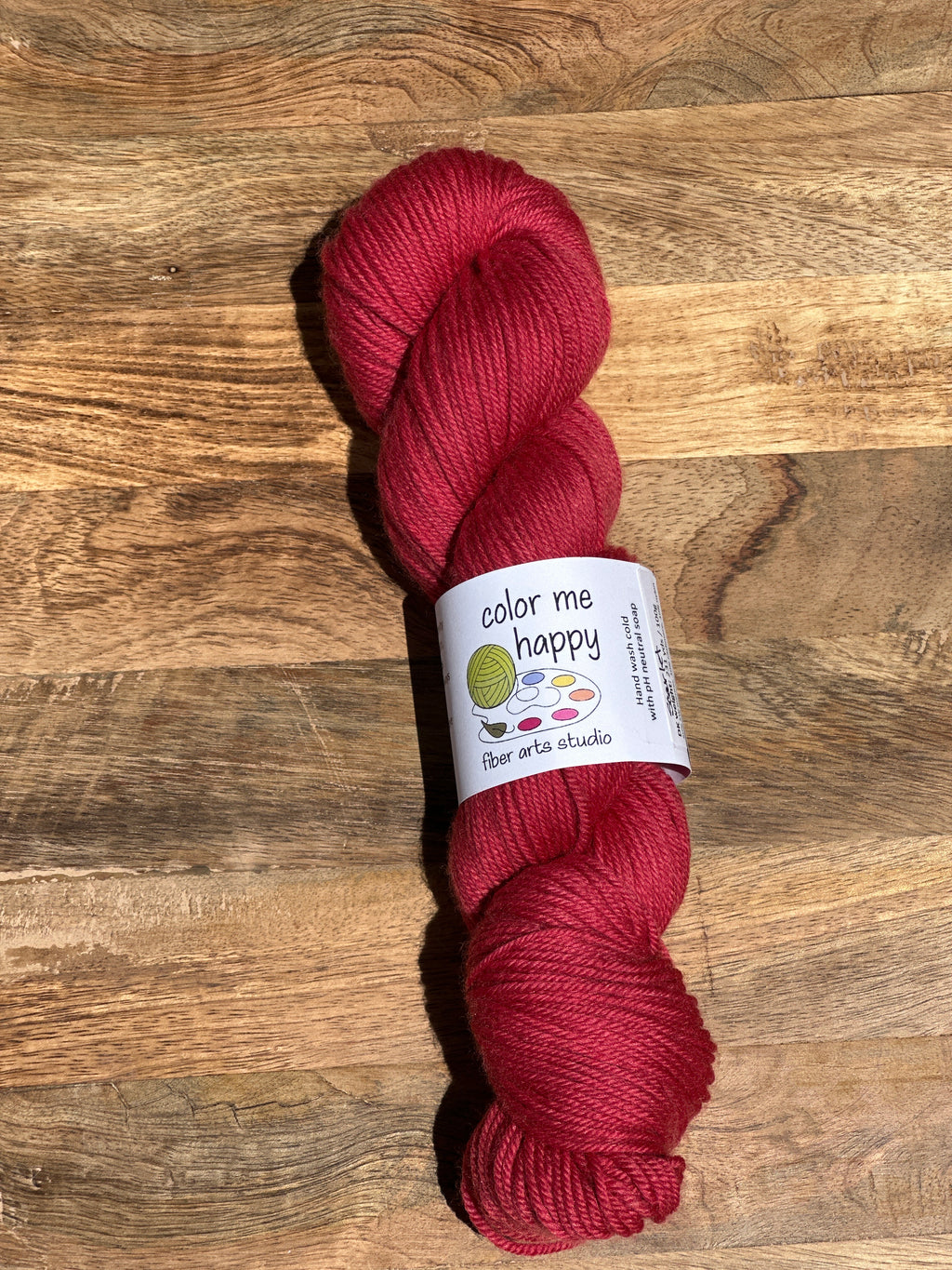 Red skein of yarn with a label on a wooden surface